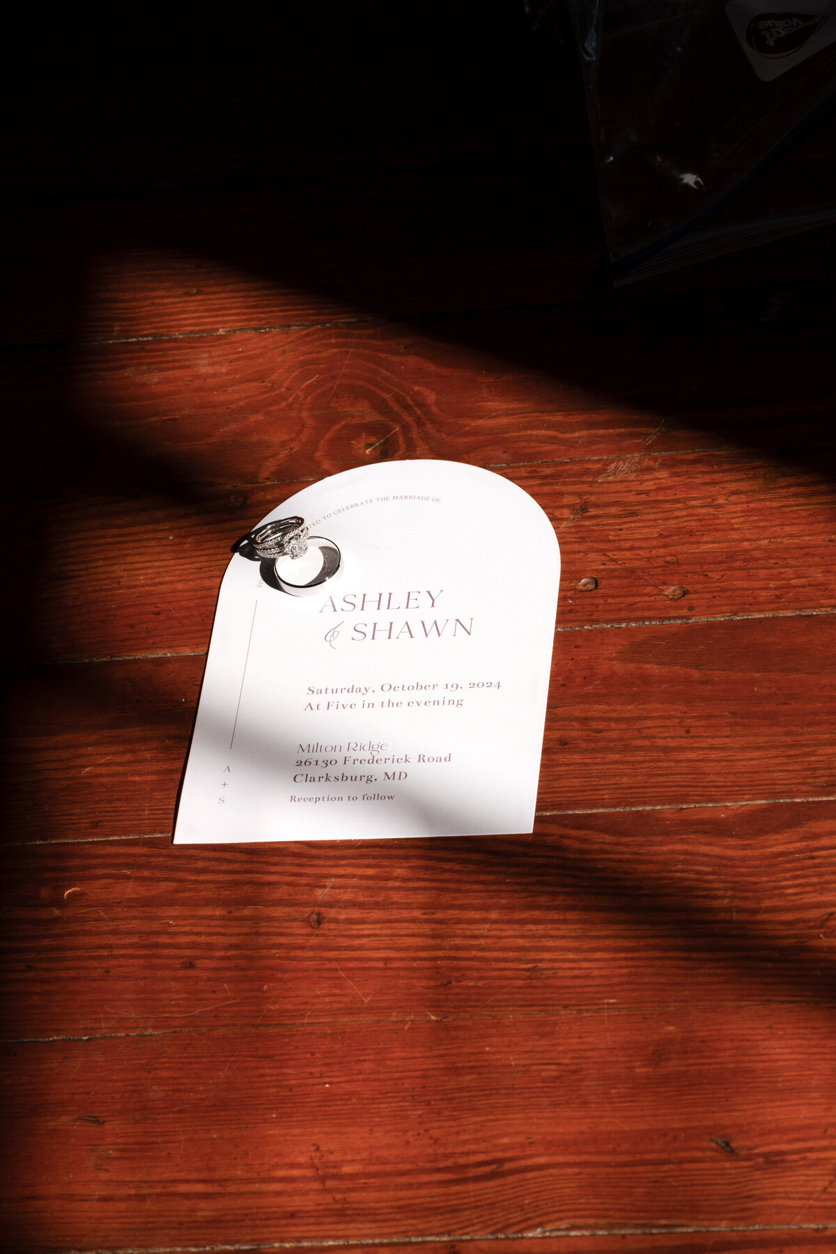 Wedding invitation suite and rings in warm window light — Maryland wedding details